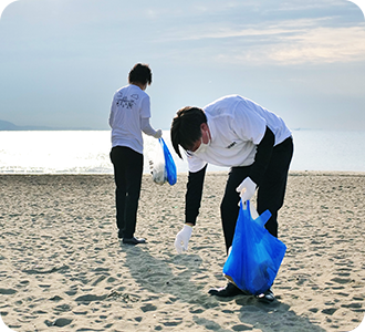 砂浜でゴミを拾う海岸美化財団の写真